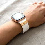 A close-up of a person's wrist wearing a smartwatch with a decorative gold metal bracelet-like accent on the wrist, the charm is silver gold plated name Rana with Airplanes engraved and colored with red enamel.