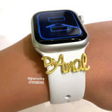 A white smartwatch band with a gold script nameplate reading 'Dr. Amal' worn on a person's wrist, with a silver smartwatch case and a black screen.
